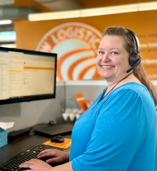 WOW Logistics employee turns her head and smiles while working in front of a computer screen
